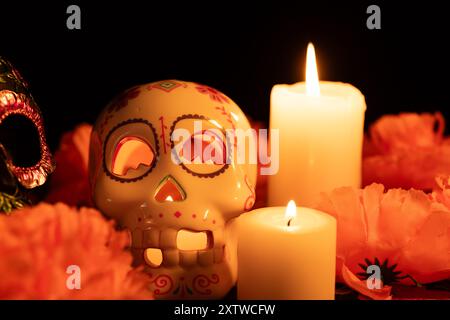 Une scène vibrante Day of the Dead avec deux crânes contrastés : l'un décoré de fleurs métalliques et l'autre avec une bougie à l'intérieur. Marigolds et éclairé Banque D'Images