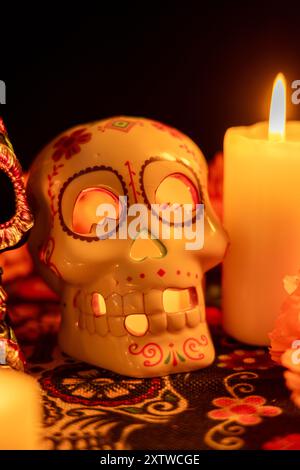 Un crâne creux avec une bougie allumée à l'intérieur est entouré de fleurs de souci, avec des bougies supplémentaires autour de lui. Toute la configuration est sur un jour des morts Banque D'Images