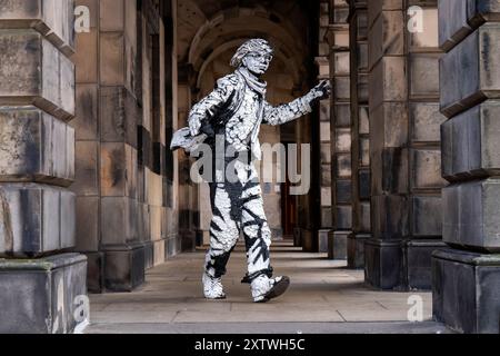 L'artiste Estevan Mortensen, originaire de l'Équateur, se produit en tant que « statue vivante » sur le Royal Mile tout au long du Festival Fringe d'Édimbourg. Son personnage de « pochoir humain » est inspiré par le Street-artiste Banksy. Date de la photo : vendredi 16 août 2024. Banque D'Images