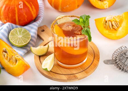 Margarita de Thanksgiving, cocktail d'arbustes de citrouille douce, boisson d'automne savoureuse à l'alcool sur fond blanc avec des tranches de citrouilles, espace de copie Banque D'Images