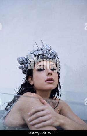 Une jeune femme aux cheveux foncés, portant une couronne de coquillages, est assise submergée dans l'eau. Banque D'Images