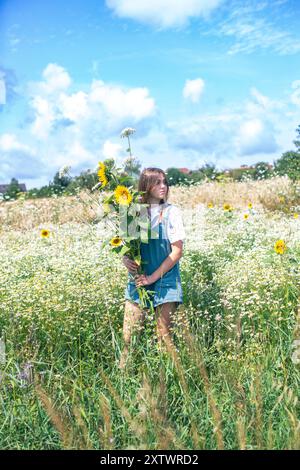 Portrait d'une jeune femme tenant un bouquet de tournesols jaunes frais Banque D'Images