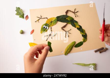 Lézard représenté de manière créative avec des matériaux naturels sur fond de papier beige. artisanat d'automne pour les enfants, idées d'activités préscolaires ou scolaires Banque D'Images