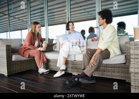 Trois collègues discutent décontractés sur un toit-terrasse dans un immeuble de bureaux moderne. Un collègue a une prothèse de jambe. Banque D'Images