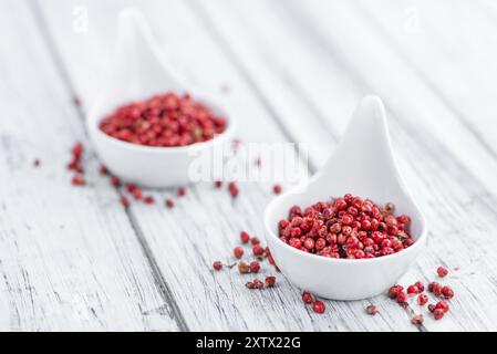 Peppercorns roses en gros plan détaillé élevé sur une table en bois vintage, mise au point sélective Banque D'Images