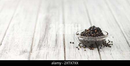 Grains de poivre noirs conservés sur fond en bois, mise au point sélective, gros plan Banque D'Images