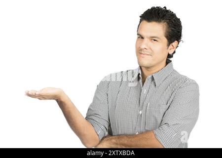 Joyeux et beau homme hispanique en chemise décontractée boutonnée regardant la caméra souriant la main ouverte sur le côté montrant un imaginaire Banque D'Images