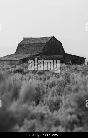 Une grange Mormon Row contre la chaîne de montagnes Grand Teton en noir et blanc Banque D'Images