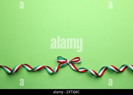 Ruban avec arc aux couleurs du drapeau hongrois sur fond vert, vue de dessus. Espace pour le texte Banque D'Images