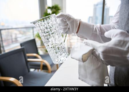 Garçon en gants blancs tenant une cruche d'eau dans un restaurant Banque D'Images