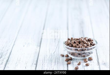 Portion de raisins secs au chocolat sur une vieille table en bois (mise au point sélective, gros plan) Banque D'Images