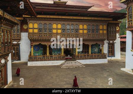 Deux moines bouddhistes dans leur robe rouge traditionnelle marchant dans la cour du monastère Punakha Dzong Banque D'Images