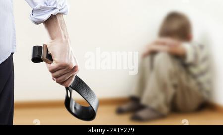 Concept de violence familiale et d'agression, furieux homme en colère levé la main de punition tenant la ceinture de cuir sur un garçon enfant effrayé ou terrifié assis à wa Banque D'Images