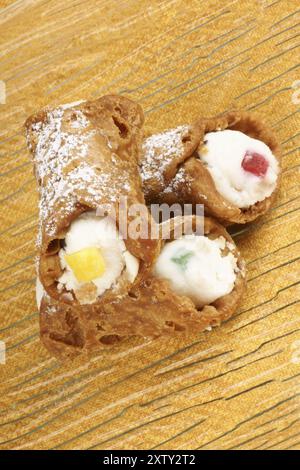 Gros plan de mini cannoli siciliens originaux sur une plaque de verre transparente sur un fond jaune. Ces pâtisseries en forme de tube sont faites de coquilles frites Banque D'Images