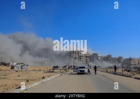 Gaza. 16 août 2024. De la fumée s'élève à proximité de la zone des tours Hamad au Nord-Ouest de la ville de Khan Younis, dans le sud de la bande de Gaza, le 16 août 2024. Les habitants de la bande de Gaza restent pris au piège d'un cauchemar sans fin de morts et de destructions, alors que de nouveaux ordres d'évacuation ont été émis par les autorités israéliennes, a déclaré vendredi l'agence des Nations Unies pour les réfugiés palestiniens. Crédit : Rizek Abdeljawad/Xinhua/Alamy Live News Banque D'Images