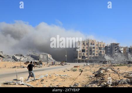 Gaza. 16 août 2024. De la fumée s'élève à proximité de la zone des tours Hamad au Nord-Ouest de la ville de Khan Younis, dans le sud de la bande de Gaza, le 16 août 2024. Les habitants de la bande de Gaza restent pris au piège d'un cauchemar sans fin de morts et de destructions, alors que de nouveaux ordres d'évacuation ont été émis par les autorités israéliennes, a déclaré vendredi l'agence des Nations Unies pour les réfugiés palestiniens. Crédit : Rizek Abdeljawad/Xinhua/Alamy Live News Banque D'Images