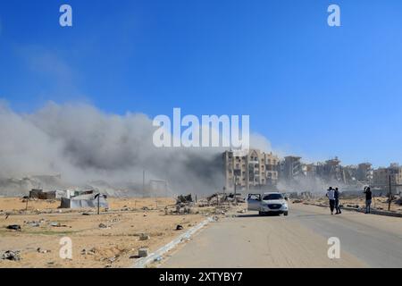 Gaza. 16 août 2024. De la fumée s'élève à proximité de la zone des tours Hamad au Nord-Ouest de la ville de Khan Younis, dans le sud de la bande de Gaza, le 16 août 2024. Les habitants de la bande de Gaza restent pris au piège d'un cauchemar sans fin de morts et de destructions, alors que de nouveaux ordres d'évacuation ont été émis par les autorités israéliennes, a déclaré vendredi l'agence des Nations Unies pour les réfugiés palestiniens. Crédit : Rizek Abdeljawad/Xinhua/Alamy Live News Banque D'Images