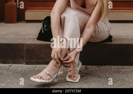 Jeune femme attachant chaussure à talon haut, détails élégants de la mode de rue, style de vie de luxe Banque D'Images