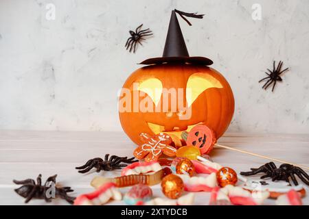 Lanterne ludique à la citrouille sculptée d'Halloween jettent une explosion de bonbons, fond blanc avec des araignées suspendues Banque D'Images