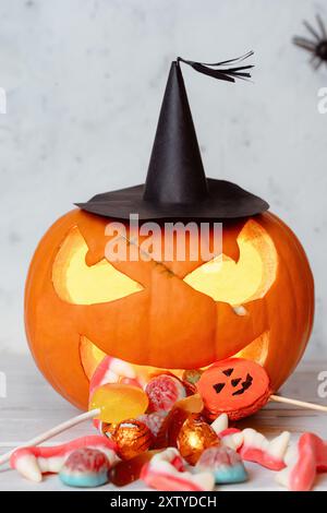Effrayant look Halloween sculpté citrouille brillante crachant comiquement des bonbons d'Halloween, bonbons colorés renversant devant Banque D'Images