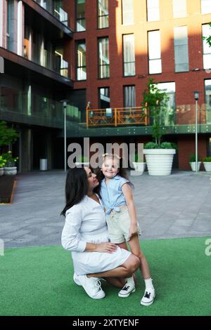 Mère et fille profitant d'un après-midi ensoleillé dans une cour urbaine moderne Banque D'Images