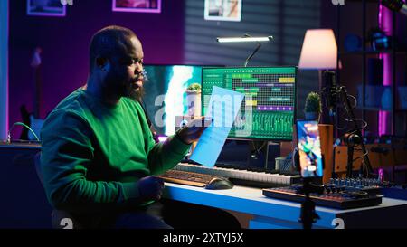 Artiste pointant à la notation de feuille musicale pour expliquer les notes sur piano, enseignant aux gens à jouer du synthétiseur dans le home studio. Compositeur musicien jouant le contrôleur midi pendant la classe de maître en ligne. Caméra A. Banque D'Images