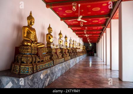 Rangée de bouddhas dorés au Temple du bouddha couché, Wat Pho, Bangkok. Banque D'Images