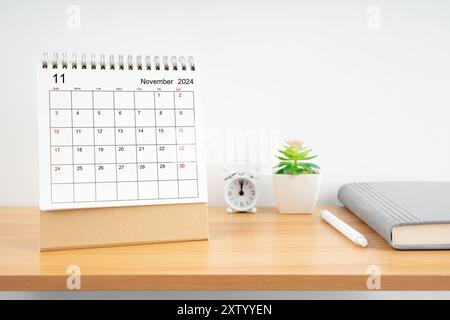 Novembre 2024, calendrier mensuel de bureau pour 2024 année sur la table en bois avec journal. Banque D'Images