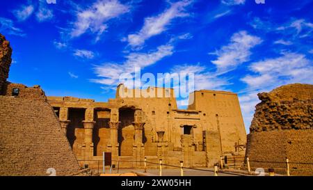 De beaux motifs de nuages et un ciel bleu vif encadrent les colonnes florales et la cour extérieure du temple d'Horus à Edfou construit pendant l'ère ptolémaïque entre 237 et 57 av. J.-C. près d'Assouan, en Égypte Banque D'Images