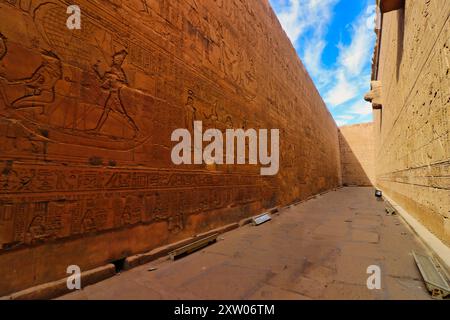 Imposants murs de grès richement décorés avec l'histoire d'Horus et des rois ptolémaïques dans le temple d'Horus à Edfou construit pendant l'ère ptolémaïque entre 237 et 57 av. J.-C. près d'Assouan, en Égypte Banque D'Images