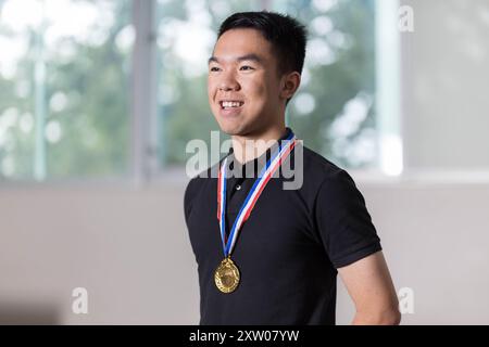 Un jeune adolescent portant fièrement une médaille d'or autour de son cou se tient fièrement debout après avoir remporté une compétition Banque D'Images