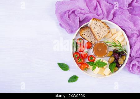 Set de collations à base de fromage, olives, tomates et caramel salé. Assiette d'apéritif ou d'antipasto Banque D'Images