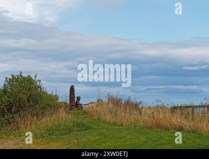 Sculpture en bois d'un pêcheur qui s'occupe de ses filets tout en regardant vers la mer au petit village de pêcheurs d'East Haven, près d'Arbroath. Banque D'Images