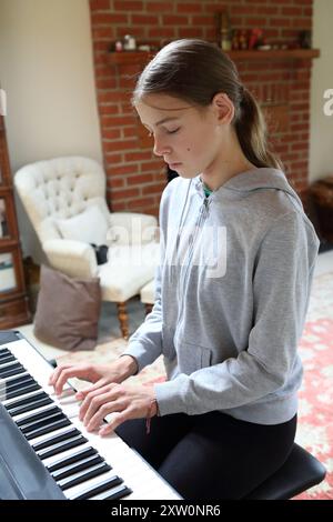 Fille joue au clavier dans le salon à la maison - touches de clavier de musique créativité musicale Tune pratique pratique Banque D'Images