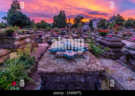 Nürnberger Stadtbild Der Johannisfriedhof à Nürnberg BEI Sonnenuntergang. IM Vordergrund ist ein altes Grab mit einem verwitterten Grabkreuz, das den gekreuzigten Jesus zeigt. Der Himmel ist in Orange- und Violetttönen gefärbt. Die Gräber sind mit Blumen geschmückt, Nürnberg Bayern Deutschland *** Nuremberg Cityscape : Johns Cemetery in Nuremberg au coucher du soleil au premier plan est une ancienne tombe avec une croix funéraire altérée montrant le Jésus crucifié le ciel est coloré en orange et violet les tombes sont décorées de fleurs, Nuremberg Bavière Allemagne 20240712-6V2A5166-HDR-M4000 Banque D'Images