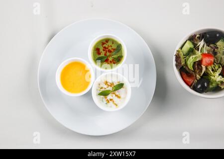 Différentes sauces savoureuses dans des bols sur une table blanche, plat. Restaurant style légumes Raita et Chutney vert, yaourt épicé menthe Chutney (Pudina Raita) Banque D'Images