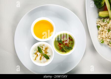 Différentes sauces savoureuses dans des bols sur une table blanche, plat. Restaurant style légumes Raita et Chutney vert, yaourt épicé menthe Chutney (Pudina Raita) Banque D'Images