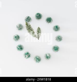 Disposition hivernale à la mode de l'horloge analogique faite avec des arbres de Noël et des branches enneigées sur fond blanc. Concept de temps minimal. Idée créative du nouvel an. Banque D'Images