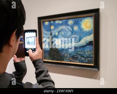 Un visiteur du Museum of Modern Art (MoMA) de New York prend une photo de « The Starry Night » de Van Gogh avec son smartphone. Banque D'Images