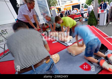 Cologne, Allemagne. 17 août 2024. Les visiteurs essaient un massage cardiaque sur des mannequins sur un stand Malteser à l'occasion de la Journée Rhénanie du Nord-Westphalie. Crédit : Henning Kaiser/dpa/Alamy Live News Banque D'Images