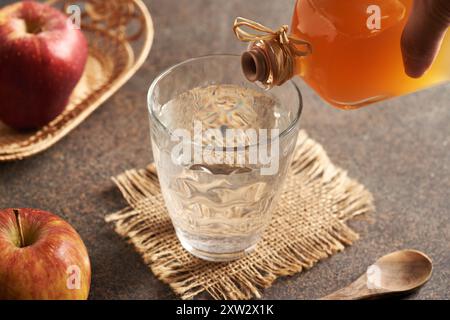 Verser le vinaigre de cidre de pomme dans un verre d'eau Banque D'Images