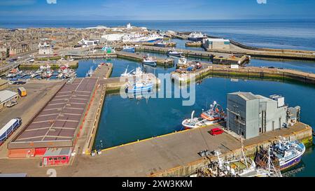 Fraserburgh Harbour Aberdeenshire Écosse Faithlie Basin et jetée le long bâtiment du marché aux poissons avec le phare au loin Banque D'Images