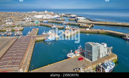 Fraserburgh Harbour Aberdeenshire Écosse les jetées du marché aux poissons avec des bateaux amarrés et phare au loin Banque D'Images