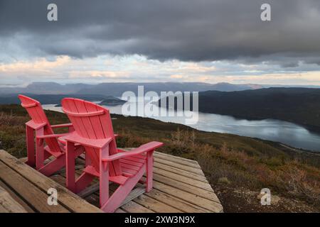 Deux chaises adirondack rouges sur une terrasse en bois surplombant bonne Bay ; Terre-Neuve-et-Labrador, Canada Banque D'Images