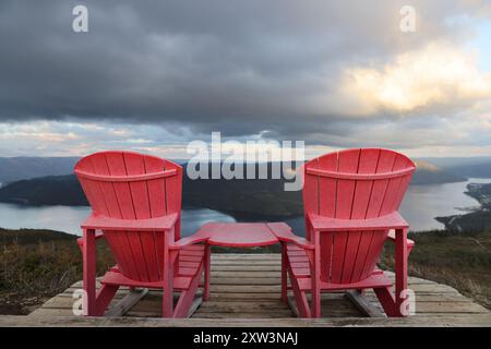 Deux chaises adirondack rouges sur une terrasse en bois surplombant bonne Bay ; Terre-Neuve-et-Labrador, Canada Banque D'Images