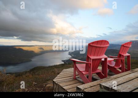 Deux chaises adirondack rouges sur une terrasse en bois surplombant bonne Bay ; Terre-Neuve-et-Labrador, Canada Banque D'Images