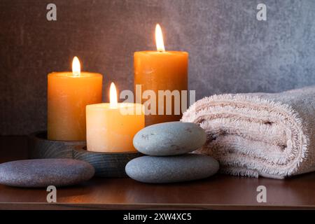 Spa Still Life avec des bougies, des serviettes et des galets sur fond de bois Banque D'Images