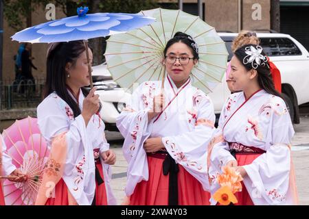 Belfast Mela Carnival Parade - trois dames en robe japonaise traditionnelle avec des parasols en bois délicats et colorés. Belfast, Royaume-Uni - 17 août 2024. Banque D'Images