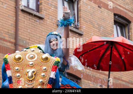 Belfast Mela Carnival Parade - flotteur d'éléphant bleu avec dame sur le dessus avec les cheveux bleus, ailes de fée entourées de bulles. Belfast, Royaume-Uni - 17 août 2024. Banque D'Images