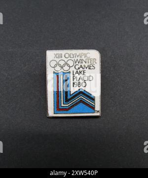 Un badge vintage en émail épingle de revers fait en souvenir des XIIIe Jeux Olympiques d'hiver qui se sont tenus entre le 13 et le 24 février 1980, à Lake Placid, New York, États-Unis. Le badge est sous la forme de l'emblème officiel des Jeux. Banque D'Images